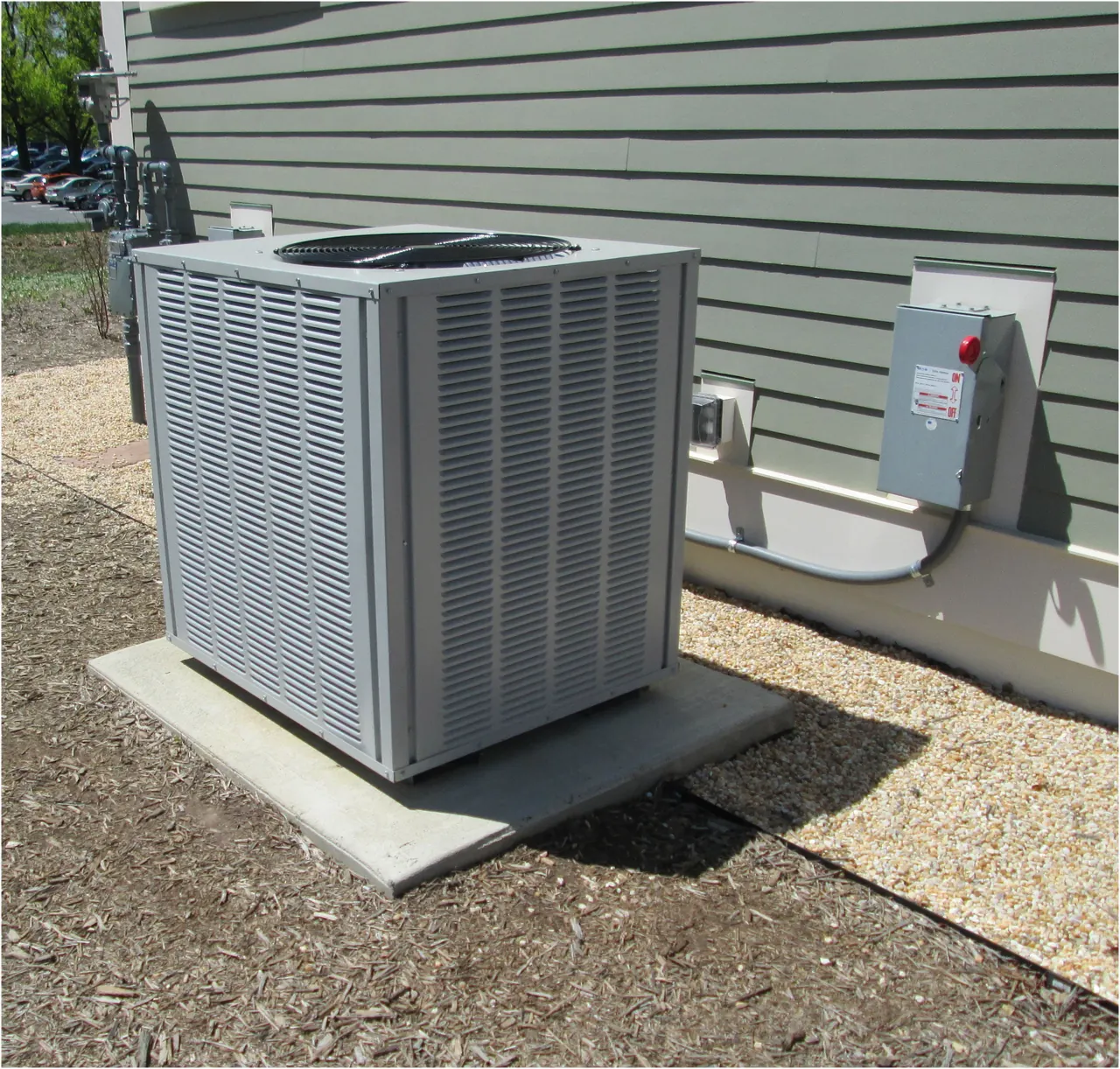 Central AC condenser on a concrete pad beside a home's siding