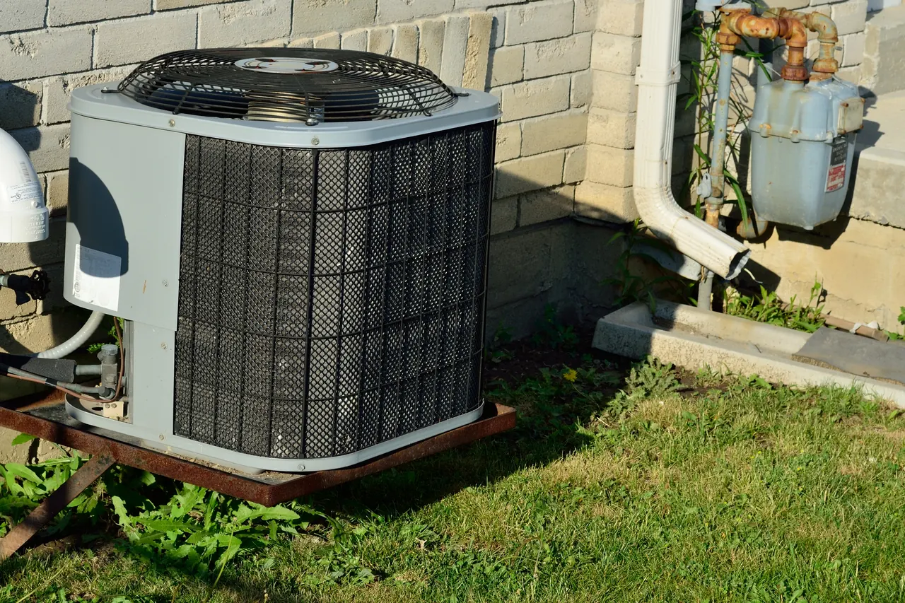 Outdoor air conditioner condenser next to a house wall and gas meter